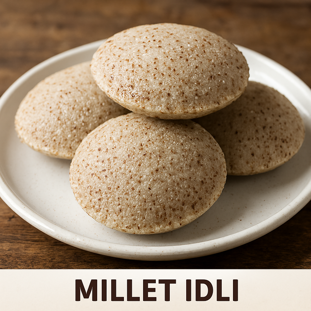 Four steamed millet idlis stacked on a white ceramic plate, showcasing their speckled texture and earthy tone, placed on a rustic wooden surface.