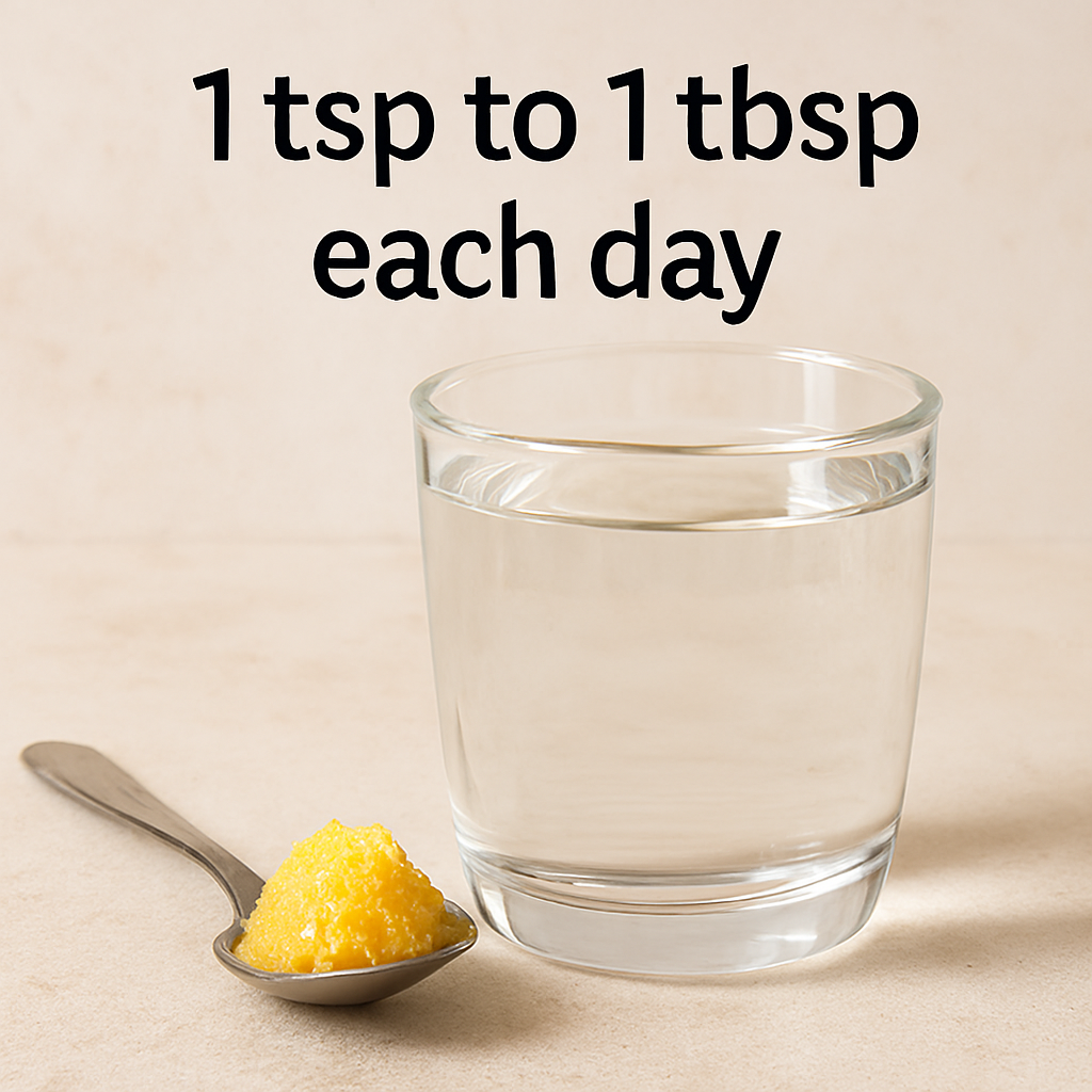 A clear glass of warm water beside a silver teaspoon holding golden-yellow ghee, with the text “1 tsp to 1 tbsp each day” overlaid above on a light beige background.